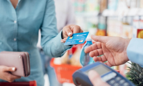 woman uses her credit card to check out at the grocery store