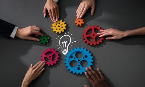 diverse hands gears light bulb on table