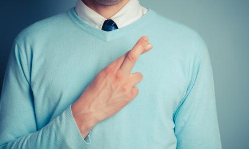 man with fingers crossed over his mint sweater