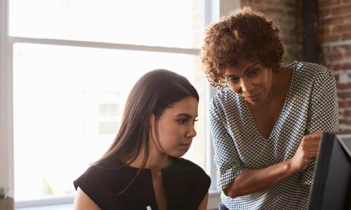 Black businesswoman leader mentoring a young female colleague at the office