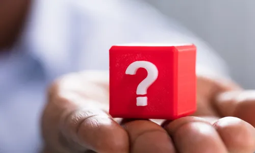hand holding red block with white question mark