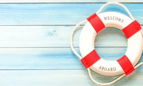 life ring buoy printed with words welcome aboard laying on blue wooden background