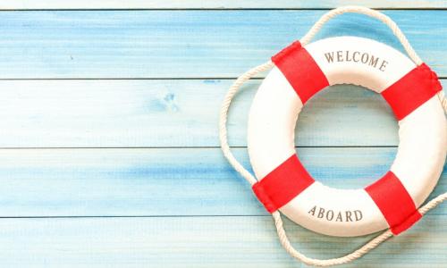 life ring buoy printed with words welcome aboard laying on blue wooden background