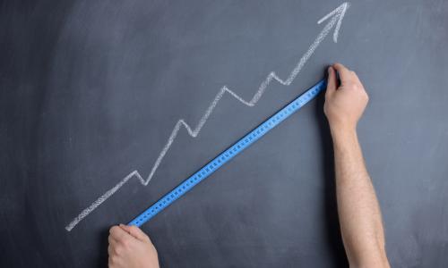 man measures blue arrow on chalkboard