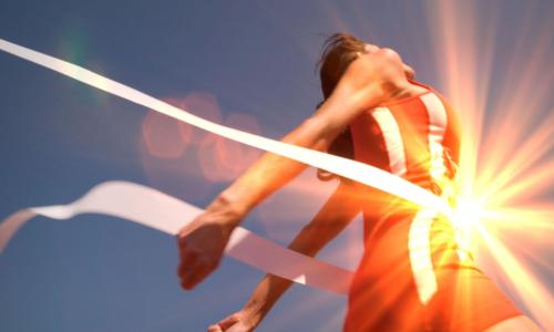 runner breaks the finish line tape