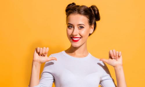 woman in pig tails with thumbs to self