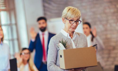 older person leaving workspace with box