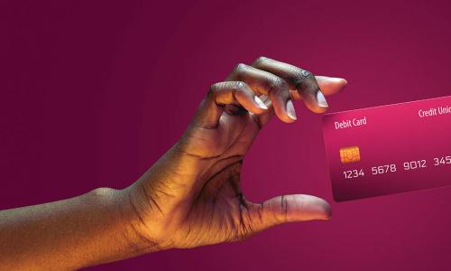 woman’s hand holding up a fuchsia debit card