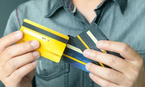 Man wearing green shirt is holding several credit cards to choose one 