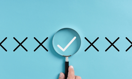 line of X's with a magnifying glass over the check mark