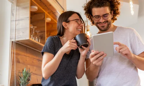 2 individuals laughing looking at a tablet