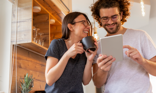 2 individuals laughing looking at a tablet